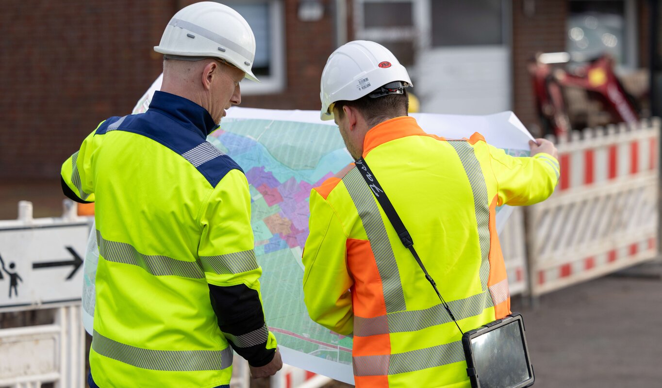 Zwei Mitarbeiter schauen sich einen Plan an.