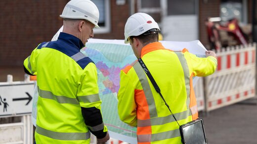 Zwei Mitarbeiter schauen sich einen Plan an.