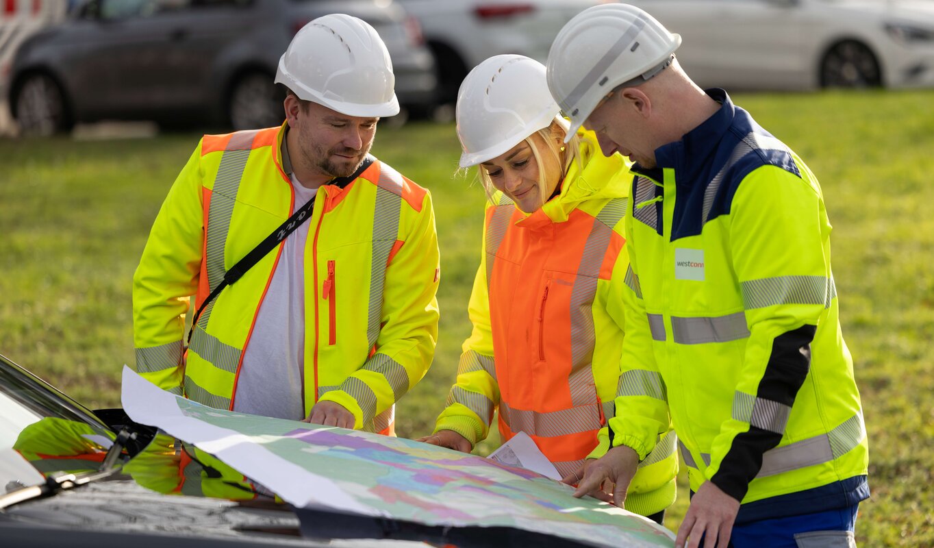 Drei Mitarbeiter schauen sich einen Plan an.