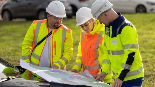 Drei Mitarbeiter schauen sich einen Plan an.