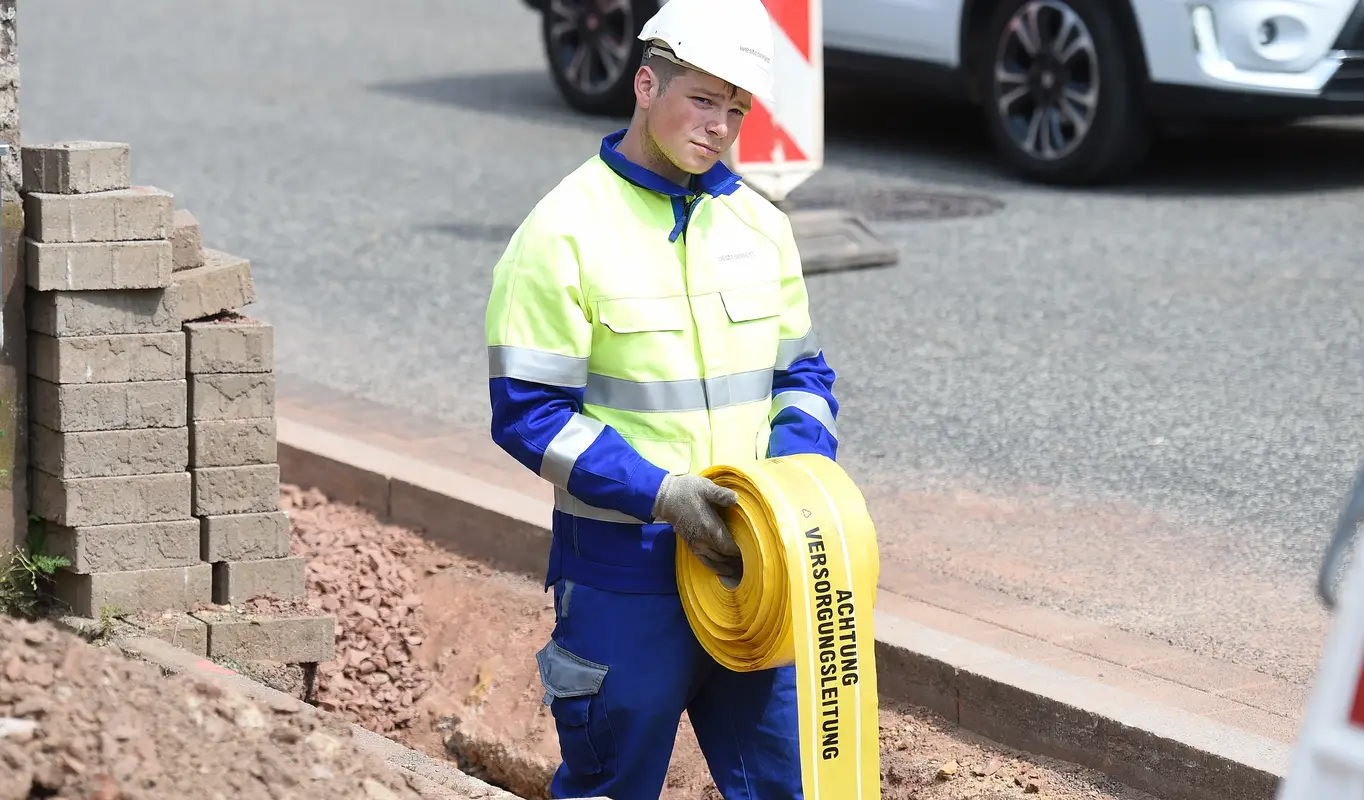 Mitarbeiter verlegt ein Trassenwarnband.