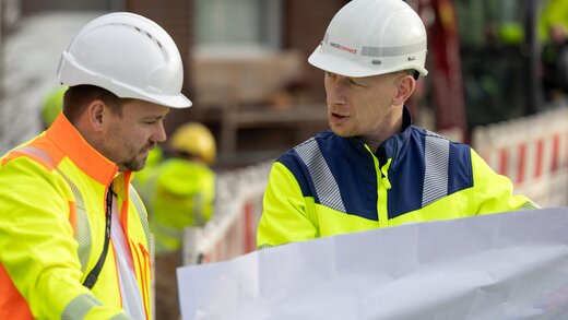 Zwei Mitarbeiter schauen sich einen Plan an.