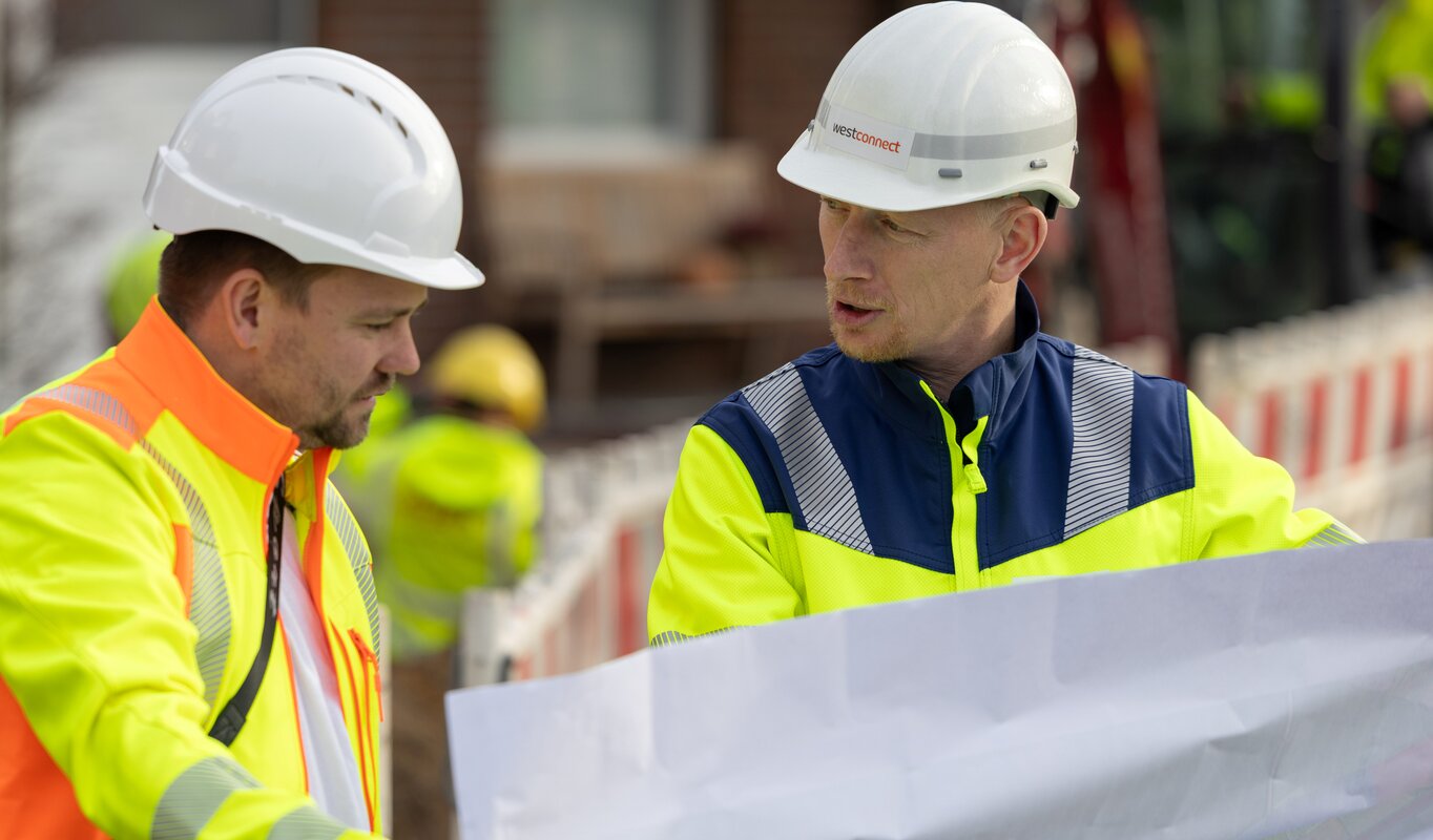 Zwei Mitarbeiter schauen sich einen Plan an.