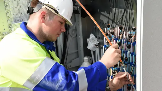 Ein Mitarbeiter bringt einen Rohradapter wird an einem Verteilerschrank an.