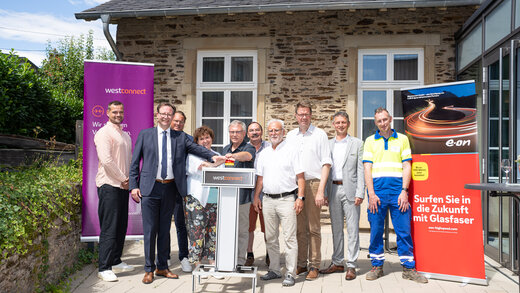 Auf dem Foto sind zehn Personen zusehen, darunter Kevin Schwiderski (Landkreis Bernkastel-Wittlich), Andreas Hackethal (Landrat des Landkreises Bernkastel-Wittlich), Sven Bender (Westconnect GmbH), Beatrix Kimnach (Ortsvorsteherin Wolf), Edgar Langen (stellv. Ortsvorsteher), Edgar Koch (3. Beigeordneter Stadt Traben-Trarbach), Patrice-Christian-Roger Langer (Stadtbürgermeister Traben-Trarbach), Marcus Heintel (Bürgermeister Verbandsgemeinde Traben-Trarbach), Marco Felten (Westenergie AG) und Andreas Müller (Westnetz GmbH).